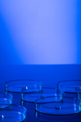 Vertical image of close up of laboratory dishes with blue liquid and copy space on blue background