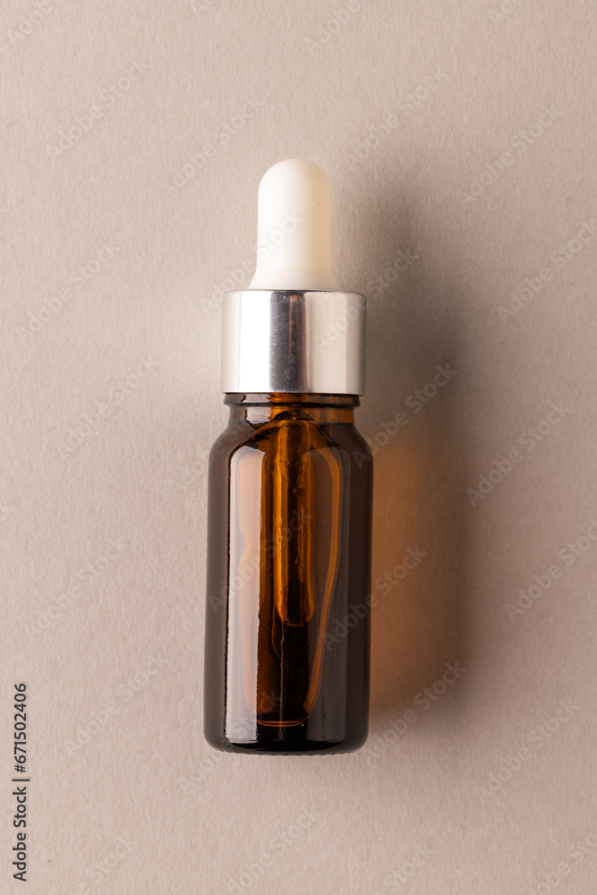 Poster vertical image of bottle with pipette and with copy space on brown background