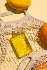 Close up of beauty product bottles, oranges and net bag with copy space on yellow background