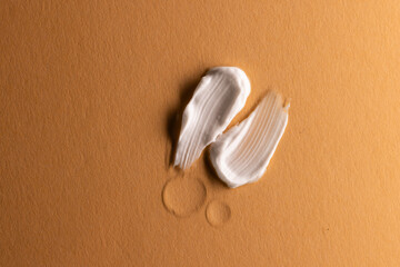 Close up of beauty product white cream smudges with copy space on brown background