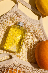 Close up of beauty product bottles, oranges and net bag with copy space on yellow background