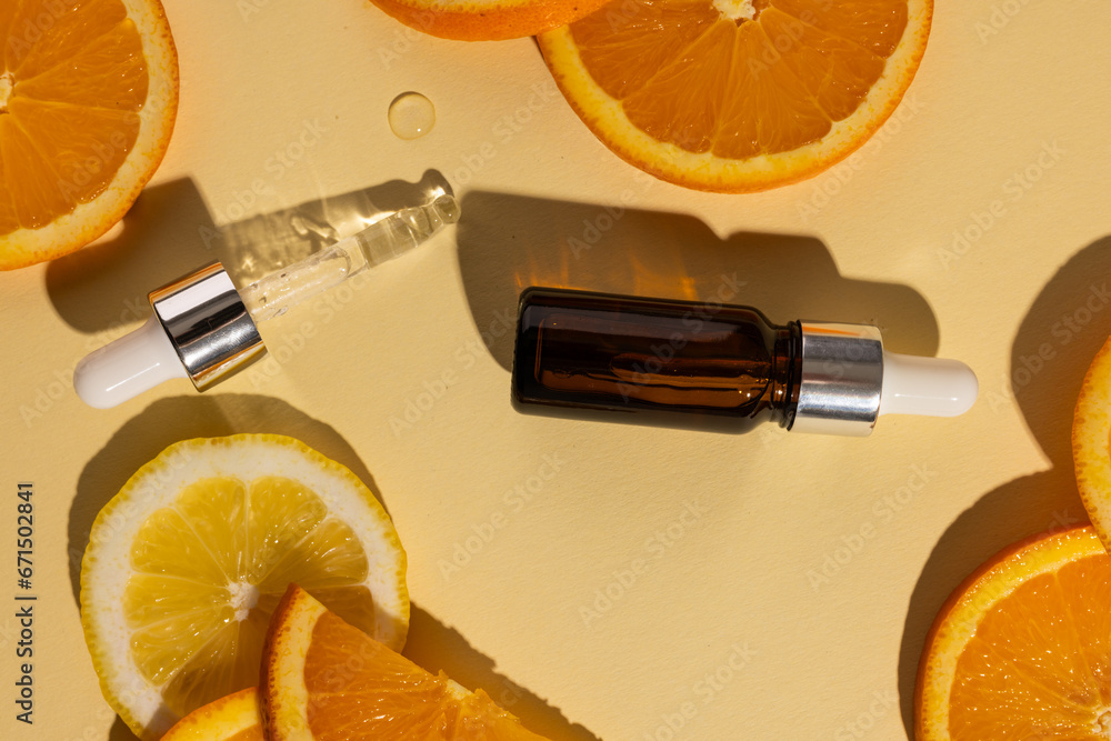 Poster bottle with pipette and oranges with copy space on yellow background