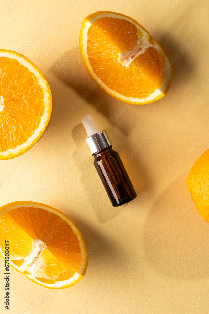 Poster vertical image of bottle with pipette and oranges with copy space on yellow background