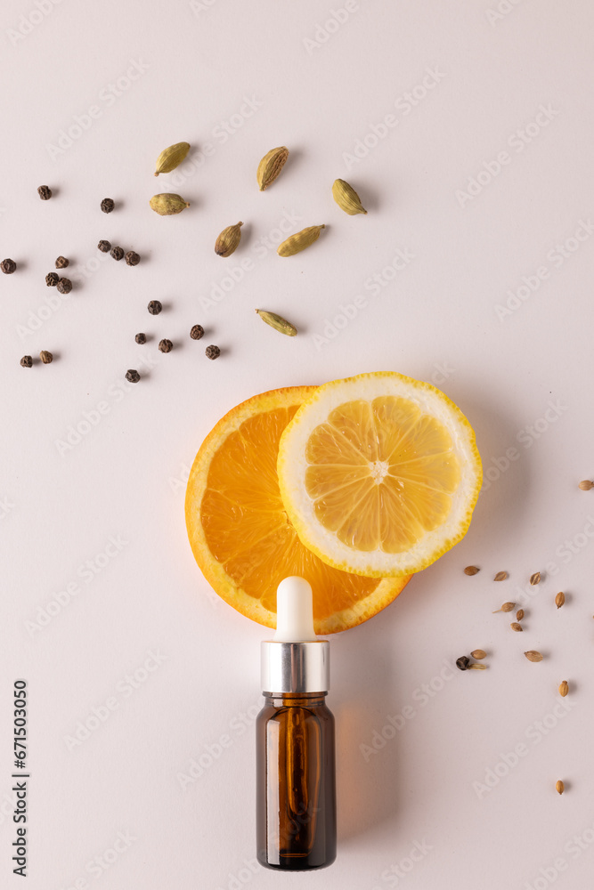 Poster vertical image of bottle with pipette and oranges and seeds with copy space on white background