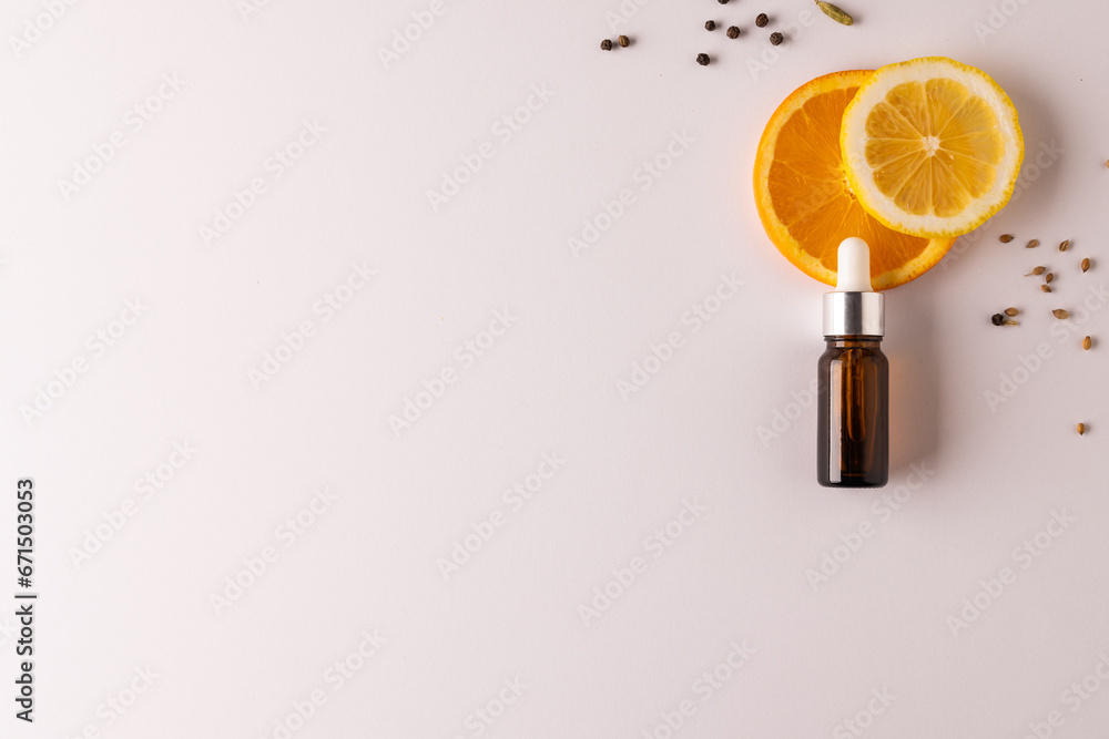 Poster close up of bottle with pipette and oranges and seeds with copy space on white background