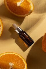 Close up of bottle with pipette and oranges and copy space on orange background