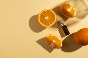 Close up of bottle with pipette and oranges and copy space on orange background