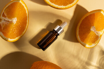 Close up of bottle with pipette and oranges with copy space on yellow background
