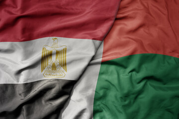 big waving national colorful flag of egypt and national flag of madagascar .