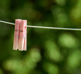 Closeup of washing line with pins hanging outside against a bokeh green background. Empty...