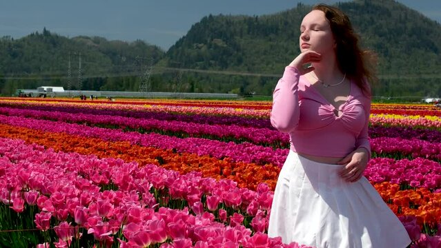 Little cute girl with long curly hair wearing a light pink skirt walks between whites and pinks hyacinthus in beautiful colorful hyacinth field in the netherlands. High quality 4k footage