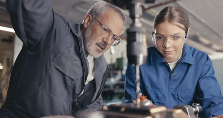 Instructor showing apprentice to cool metal drill in workshop - Powered by Adobe
