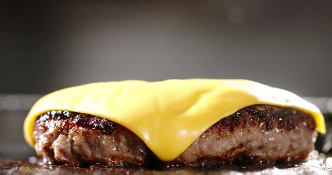 Macro shot of frying beef halal cutlets with melted cheese on top. Cinematic advertising burger cooking. Traditional meal with these pan-fried halal beef cutlets. Fan of fried food, cholesterol