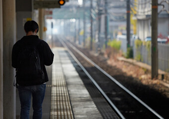 朝の通勤時間帯の駅のホームで歩く男性の姿