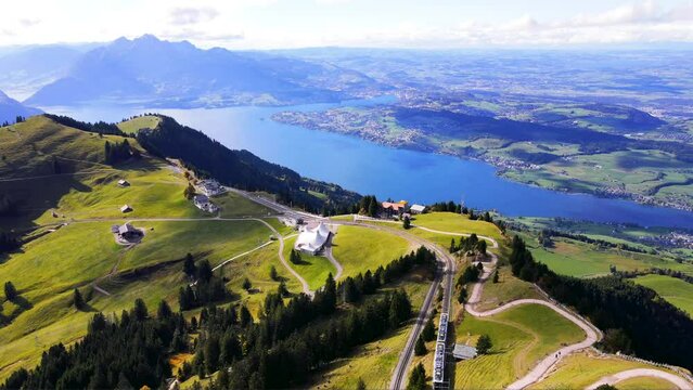 panoramic aerial view of a spectacular funicular train journey from high altitude station above Mount Rigi featuring the Lake of Lucerne and Mount Pilatus in the Swiss Alps 