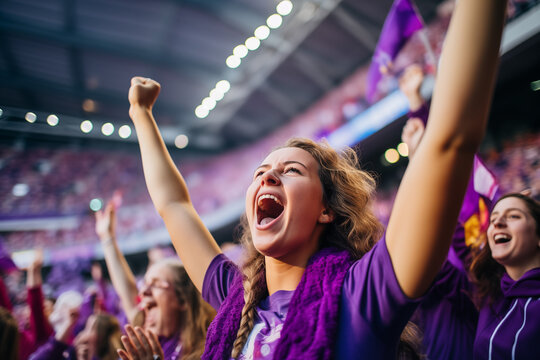 woman and group of fans celebrating and screaming supporting team in stadium seats wearing purple 