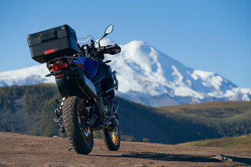 Traveling in the mountains off-road. A motorcycle on the background of a snow-covered volcano. Copy...
