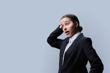 Surprised teenage female looking in profile at copy space, grey background