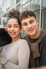 Young man and woman teenager couple take selfies by modern building