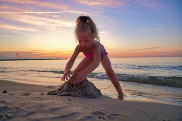 The girl is making a sand castle on the beach.