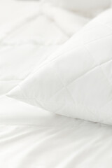 White quilted pillow on a white bedding white background. Cushion. Home textile. Macro photo