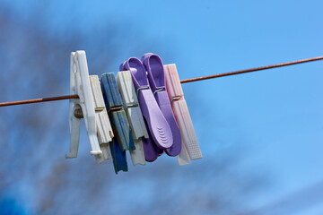 Old washing line with broken pins hanging outside against a blurred blue background. Brown...