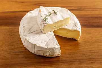 fresh delicious brie cheese and sprig of thyme on a wooden board close up shallow depth of field