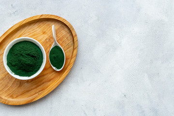 Spirulina or seaweed powder in bowl and in spoon, top view. Super food concept