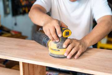 carpenter using a random orbit sander on wood in the workshop,woodworking concept , selective focus