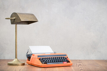 Vintage typewriter and old bronze desk lamp on wooden table front mint green background. Retro...