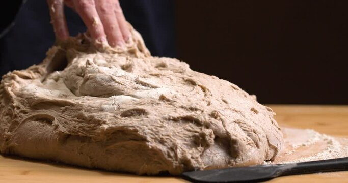 Woman pours risen bread dough on a baking board