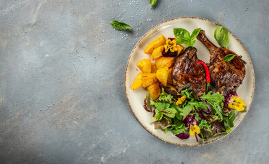 roasted duck leg with potatoes and lettuce salad. Long banner format. top view