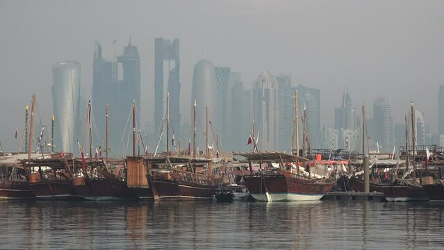 Modern Doha skyline behind classic wooden dhow vessels, capital city Qatar