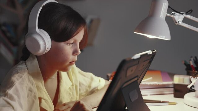 Distant School Learning Concept. Girl in Headphones Uses Tablet Computer