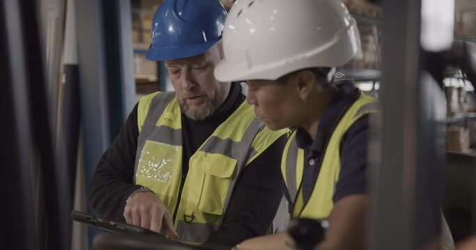 Two Warehouse Workers Looking at Digital tablet Discussing Supply chain
