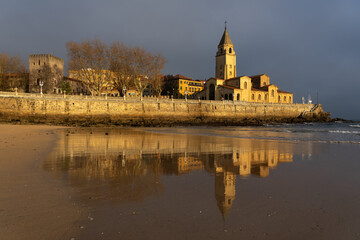 San Pedro church in the San Lorenzo beach illuminated by sun at sunrise in the city of Gijon, Asturias, Spain