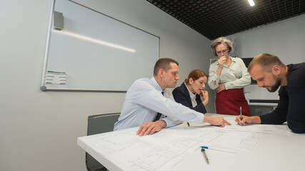 The female boss evaluates the work of subordinates. Designers engineers at a meeting. 