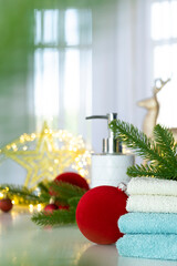 Stack of blue and white towels folded on the table, fir branches, Christmas balls and Christmas lights. SPA treatment or beauty salon, relaxation and wellbeing in Christmas or New Year variant.