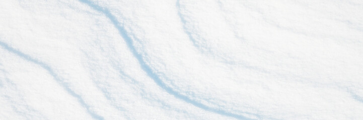 Obraz premium Wide panoramic winter background with snowy ground. Natural snow texture. Wind sculpted patterns on snow surface.