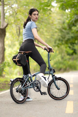 Beautiful woman ride bicycle, eco transport exercise outside in summer park. Young adult woman enjoy bike riding, outdoor sport and green energy. Environmental awareness person joy relaxation, smiling