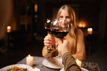 Couple in love clinking glasses at Valentine's day dinner at home, having a romantic candlelight dinner at home, drinking wine