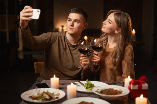 Young couple in love taking selfie while having dinner at home or in restaurant, celebrating valentine's day, enjoying time spent together