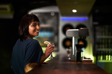 Woman, smile and drink in portrait at bar, face and happy at event, party or social gathering. Female person, alcohol and cocktail for fun, relax and travel to Ibiza, dark and joy at night on face