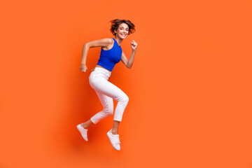 Full body profile portrait of energetic gorgeous lady jump rush empty space isolated on orange color background
