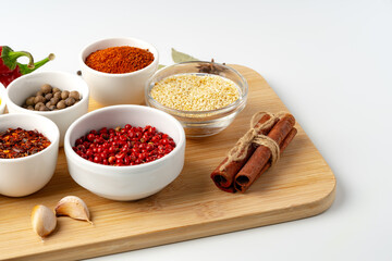 Bowls with spices on wooden board on white background