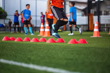 Foto op Plexiglas Soccer ball tactics on grass field with barrier for training children jump skill © chitsanupong