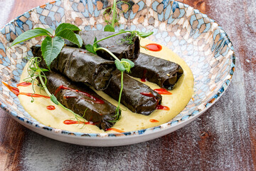 Dolma in grape leaves with lamb on mushroom julienne. Haute cuisine. On a wooden background.
