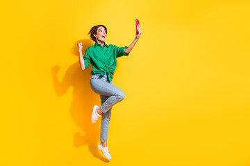 Fototapeta na wymiar Full length photo of lucky impressed lady wear green shirt jumping high recording video vlog empty space isolated yellow color background