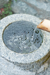 Close up shot of purification fountain with bamboo and wooden scoop in Japan