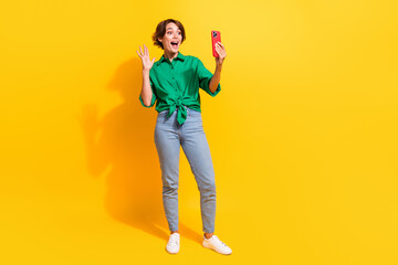 Full length photo of cute excited lady wear green shirt waving arm recording video vlog empty space isolated yellow color background